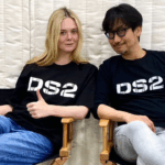 Elle Fanning e Hideo Kojima seduti su due sedie con magliette DS2 durante la promozione di Death Stranding 2